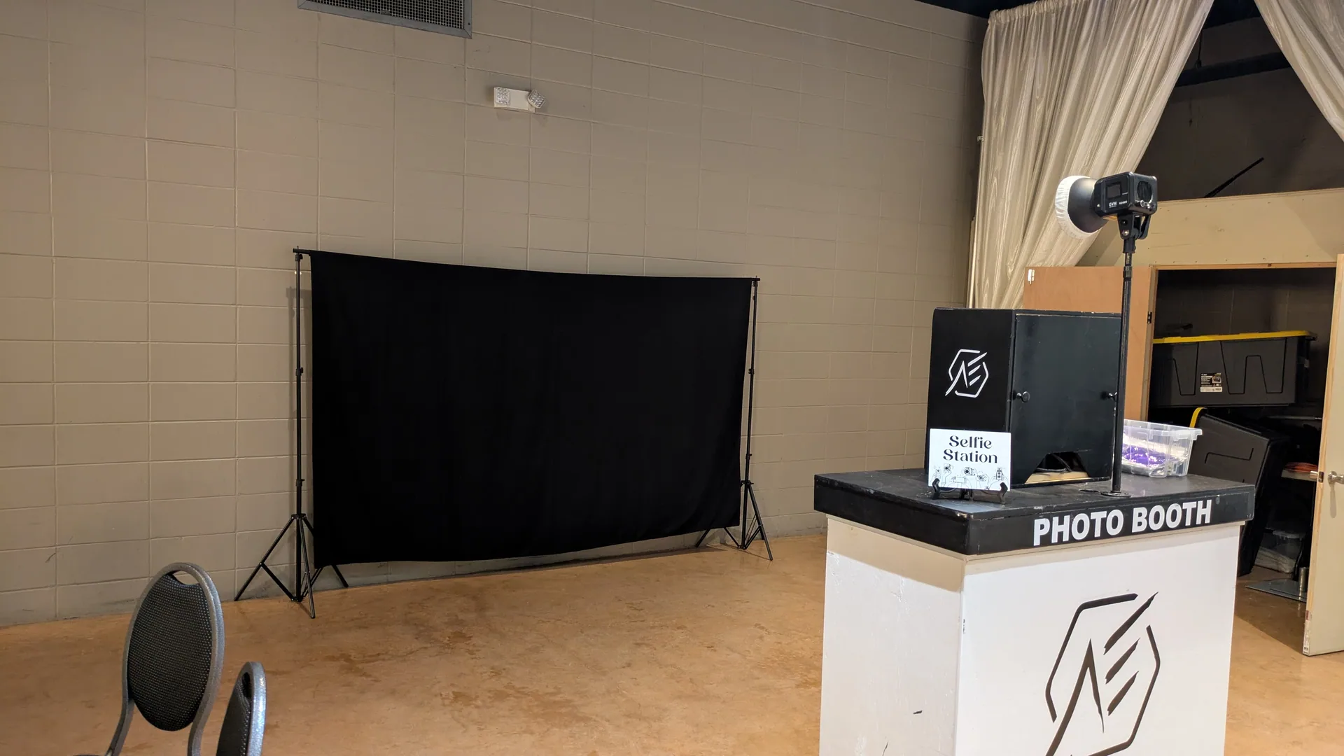 The photo booth indoors as a selfie station, with a plain black backdrop rigged opposite it.
