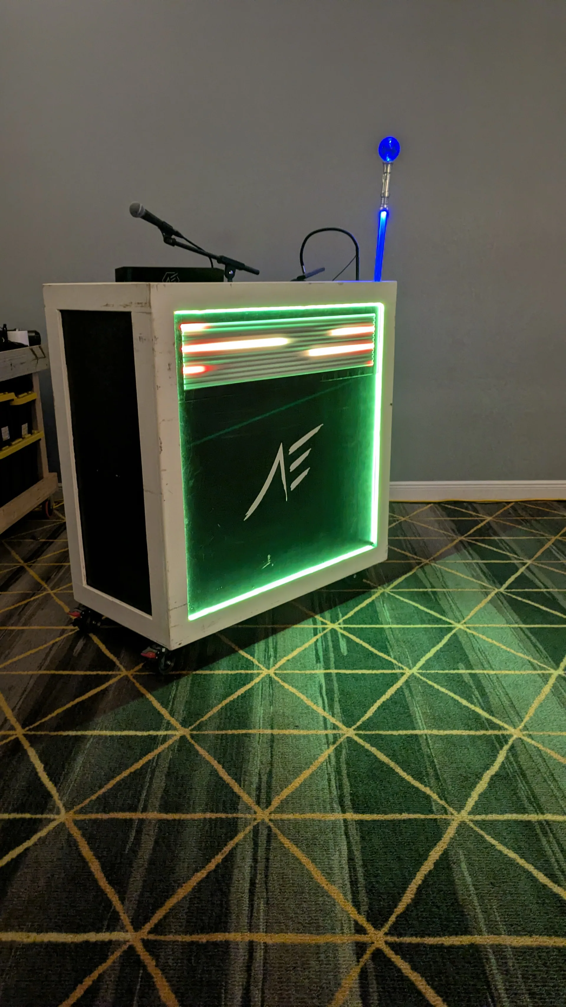 A DJ booth outlined in green LED light with a microphone set on top, ready before guests arrive.