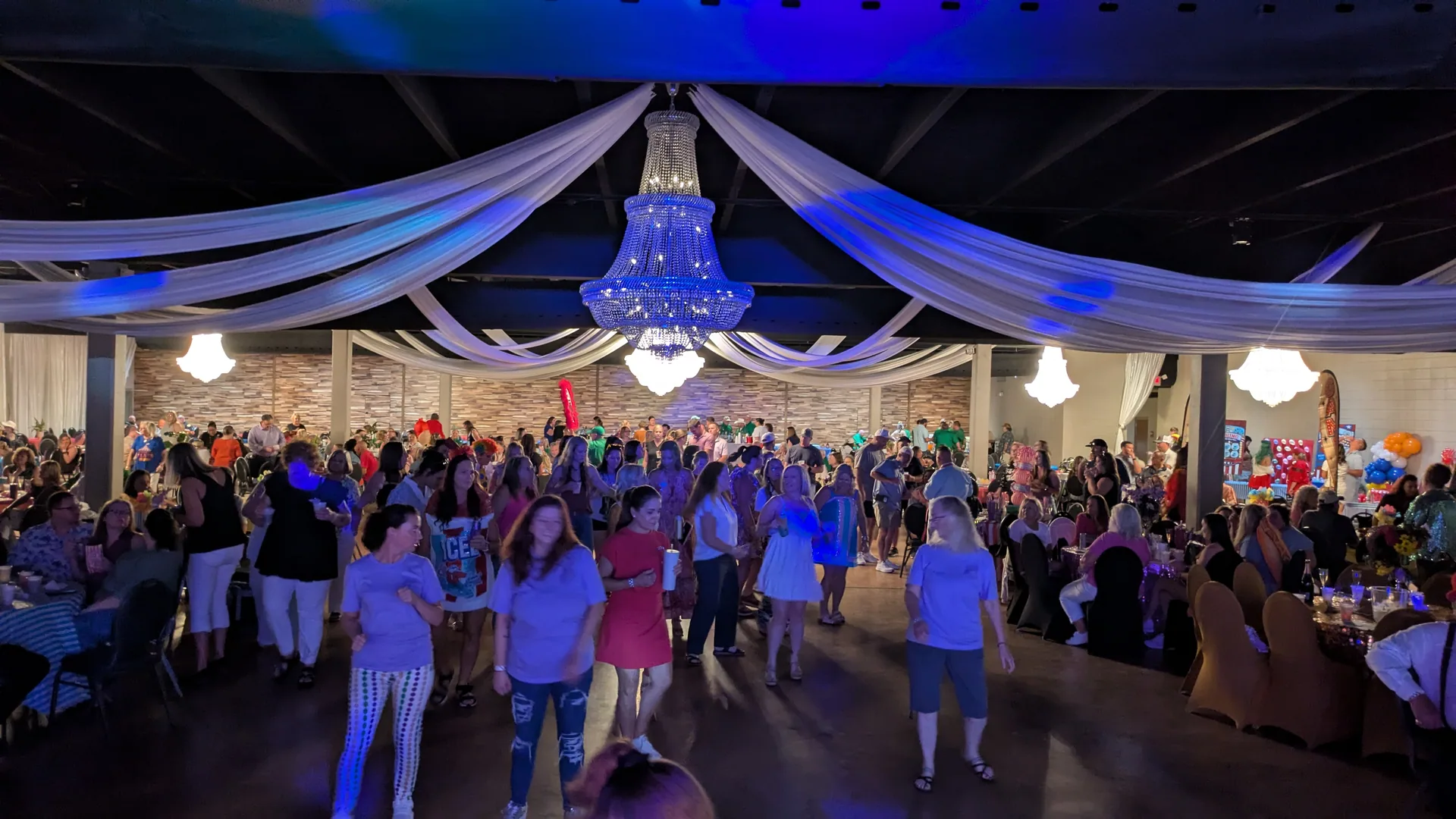 A packed ballroom under chandeliers and draped ceiling fabric, the floor full during an Anders Events booking.