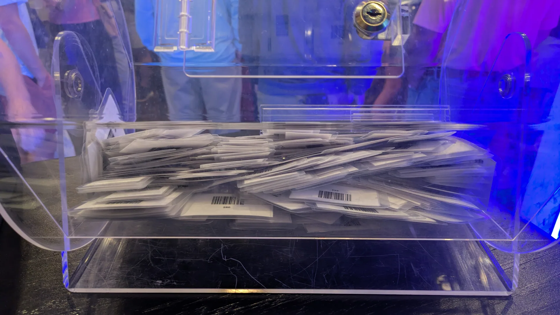A locked clear acrylic ticket hopper filled with barcoded drawing tickets.