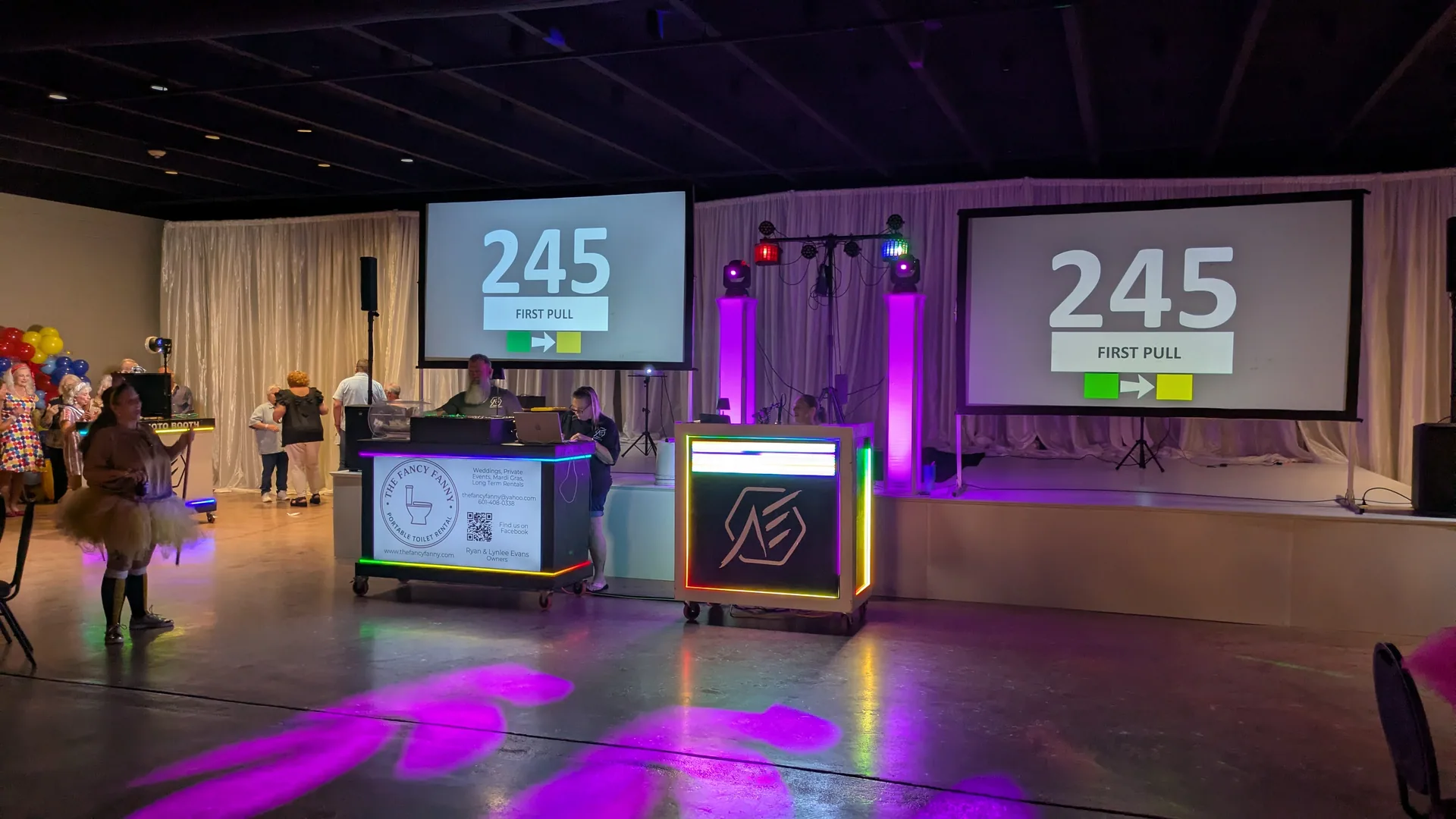 A drawing under way with the current number shown simultaneously on two large projection screens flanking the stage, the lit DJ booth between them.